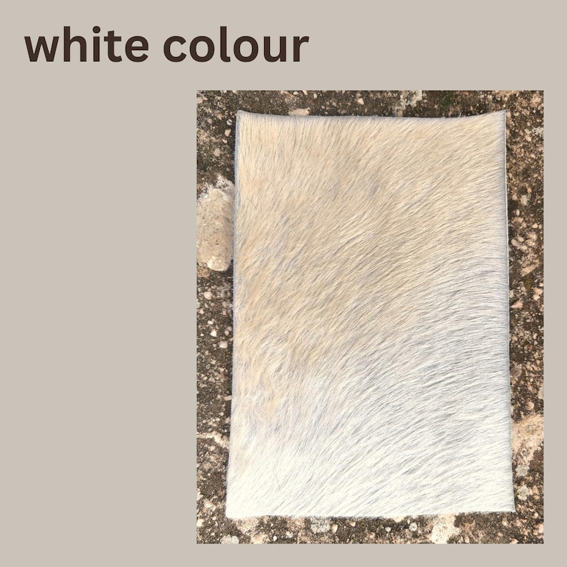 May include: A rectangular, off-white cowhide rug with a soft, textured surface. The rug has a natural, organic look with variations in the white color. The words "white colour" are in the top left corner.