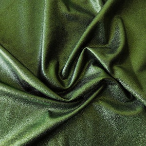 May include: Close-up of a green, metallic fabric with a wrinkled texture. The fabric has a subtle sheen and a smooth, soft feel.
