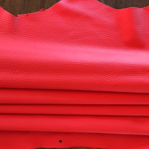 May include: A folded piece of bright red leather. The leather has a textured surface.