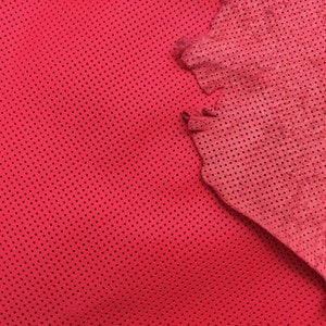 K&ouml;nnte beinhalten: Rotes perforiertes Leder mit einer strukturierten Oberfl&auml;che. Das Leder hat einen leicht dunkleren Rotton in der Mitte.