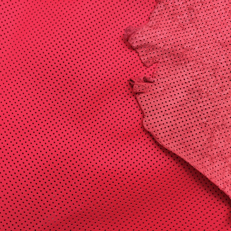 K&ouml;nnte beinhalten: Rotes perforiertes Leder mit einer strukturierten Oberfl&auml;che. Das Leder hat einen leicht dunkleren Rotton in der Mitte.