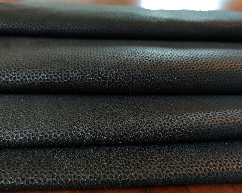 Może przedstawiać: Zbliżenie czarnego materiału o fakturowanej, chropowatej powierzchni. Materiał jest złożony w kilku warstwach, co podkreśla fakturę.