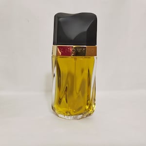 May include: A clear glass bottle of perfume with a gold cap and the word "KNOWING" printed on the cap. The bottle is filled with a yellow liquid.