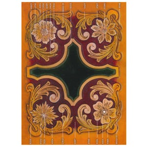May include: Close-up of a leather craft design with floral and scrollwork patterns. The design features a dark red center with a green border, surrounded by golden-yellow embellishments and flowers. The background is a warm, orange-yellow.