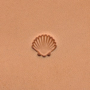 May include: A close-up of a light brown leather surface with a brown seashell design embossed into the surface.