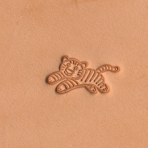 May include: A brown leather surface with a small, embossed image of a tiger cub running. The tiger cub is outlined in brown and has a striped pattern.