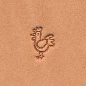 May include: A detailed image of a chicken leather stamp. The stamp is a brown outline of a cartoon chicken with a crown. The stamp is pressed into a light brown leather surface.