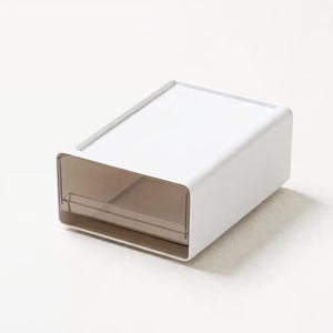 Könnte beinhalten: Eine weiße, rechteckige Aufbewahrungsbox mit einer transparenten, braun getönten Schublade. Die Box hat ein minimalistisches Design mit flacher Oberseite und abgerundeten Kanten. Die Schublade ist von vorne sichtbar und bietet einen Einblick in ihren Inhalt. Die Box ist für die Organisation kleiner Gegenstände konzipiert.