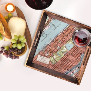 May include: A wooden serving tray with a vintage map of New York City printed on the bottom. The map shows the streets of Manhattan and Central Park. The tray has two handles on the sides.