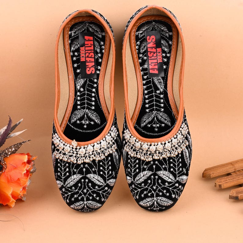 May include: Black velvet shoes with silver embroidery and a silver beaded trim. The shoes have a brown leather insole with the text "ARTISANS TOUCH" printed in red.
