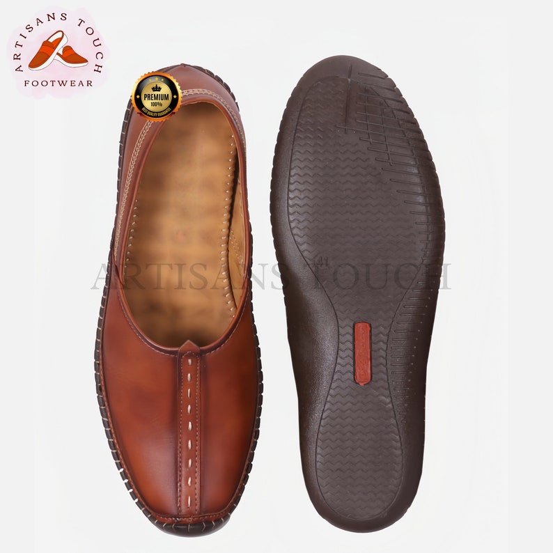 May include: A pair of brown leather slip-on shoes, one showing the top and the other the sole. The top shoe has white stitching and a decorative seam. The sole is dark brown with a textured pattern. The logo "ARTISANS TOUCH FOOTWEAR" is visible.