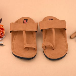 Op de afbeelding: Een paar bruine leren sandalen met een teenlus en een enkelband. De sandalen hebben een eenvoudig ontwerp en zijn gemaakt van een zacht, comfortabel materiaal.