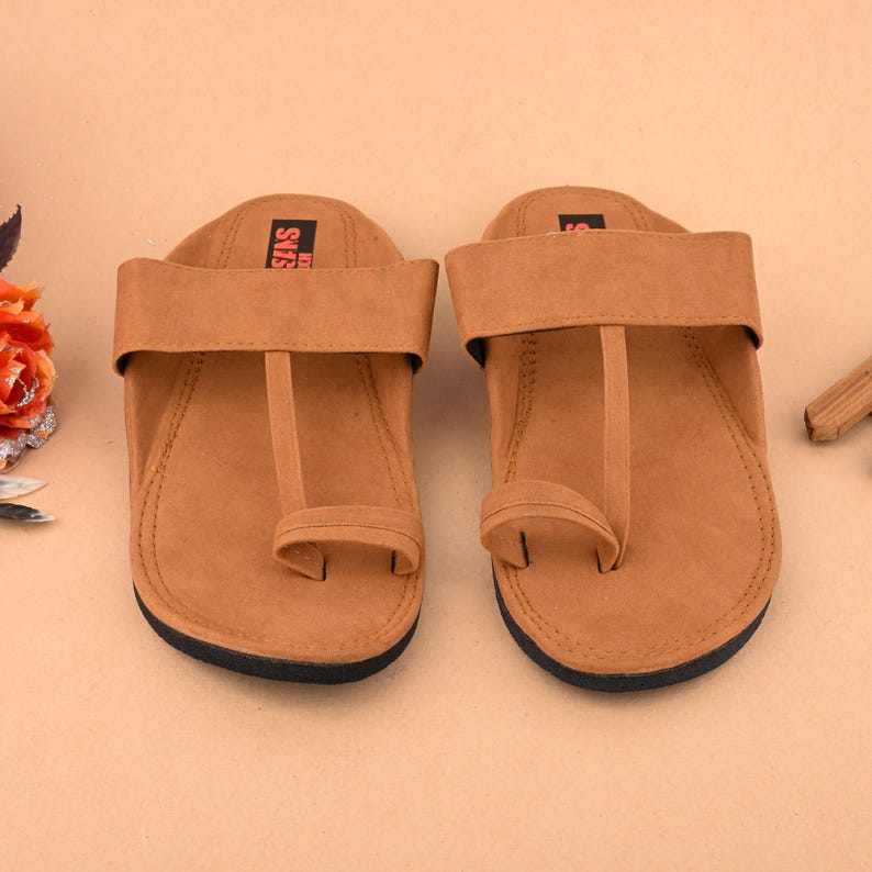 Op de afbeelding: Een paar bruine leren sandalen met een teenlus en een enkelband. De sandalen hebben een eenvoudig ontwerp en zijn gemaakt van een zacht, comfortabel materiaal.
