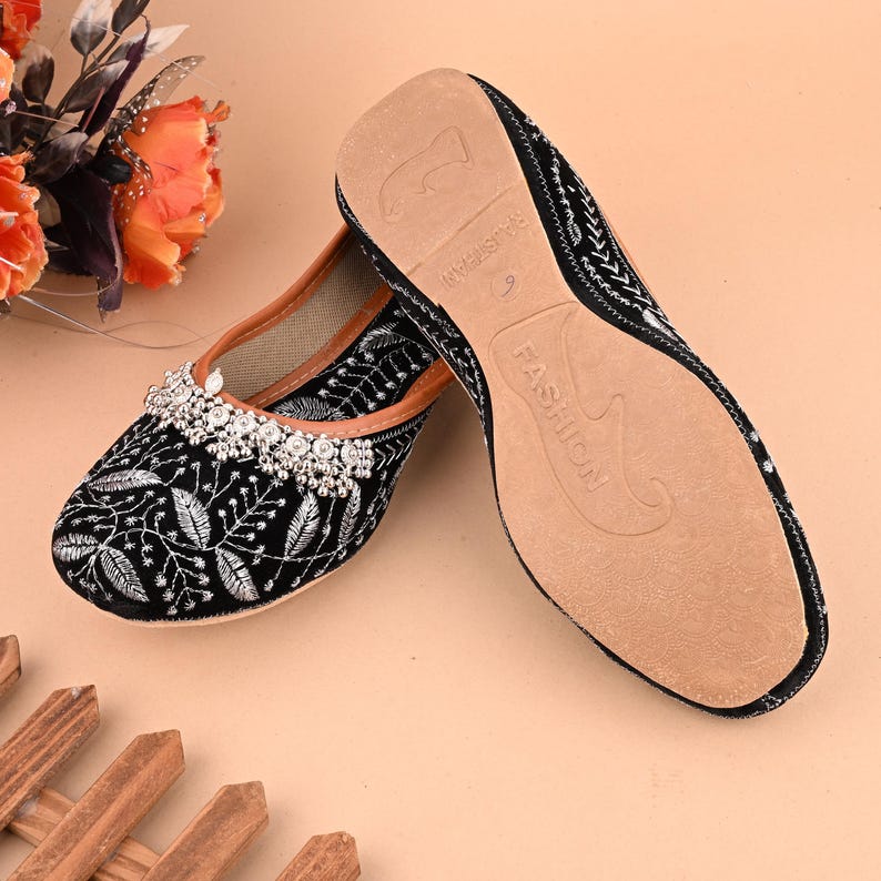 May include: Black velvet shoes with silver embroidery and a beaded embellishment. The shoes have a brown leather sole with the word "FASHION" printed on it.