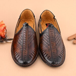 K&ouml;nnte beinhalten: Ein Paar braune Slipper aus Leder mit perforiertem Design und N&auml;hten.