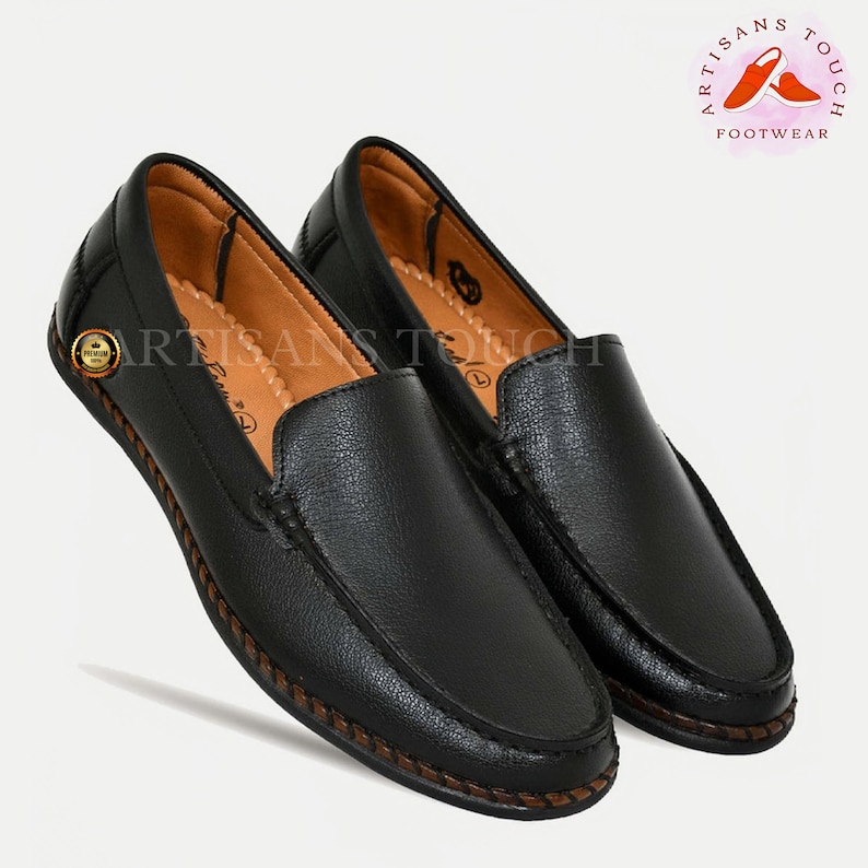May include: A pair of black leather loafers with a brown stitched trim. The loafers have a slip-on design and a rounded toe.