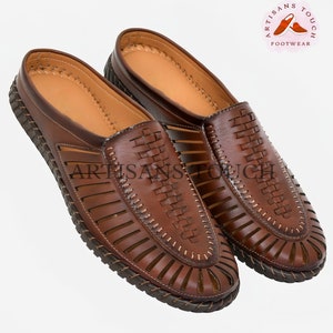 May include: A pair of brown leather sandals with a woven design and cutouts. The sandals have a closed toe and a slip-on style.