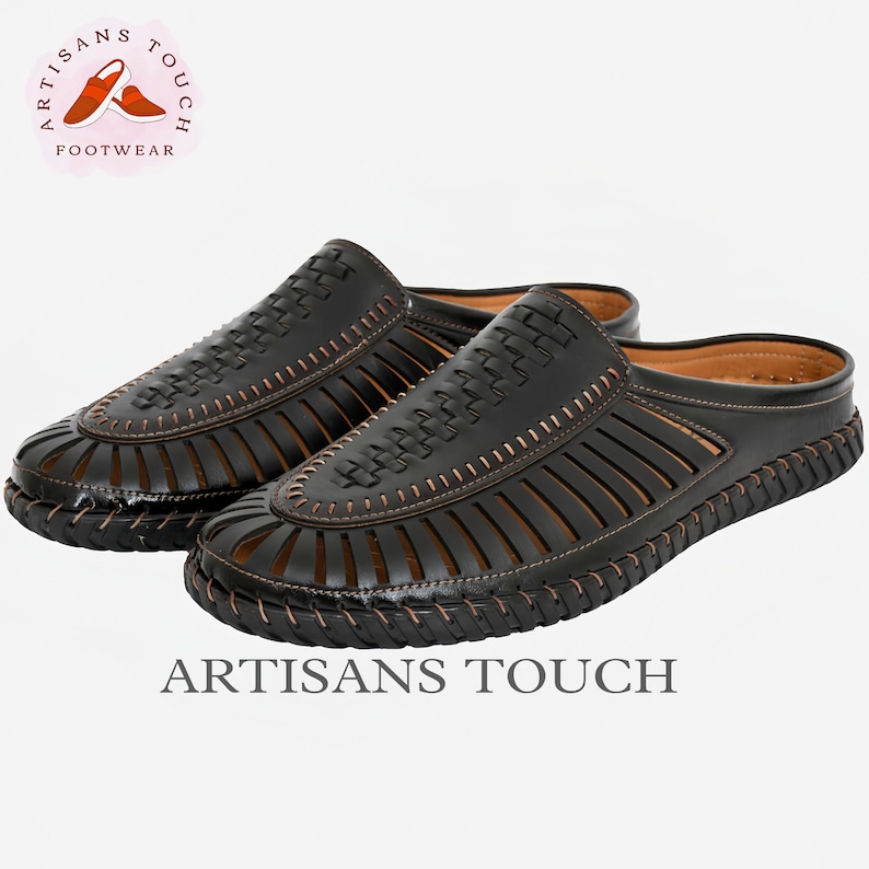 May include: A pair of black leather sandals with a woven design and a brown stitching detail. The sandals have an open toe and a back strap. The sandals are made by Artisans Touch Footwear.