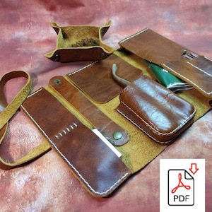 May include: A brown leather roll-up case with multiple compartments for tools or supplies. The case has a strap and a small, square, brown leather tray.