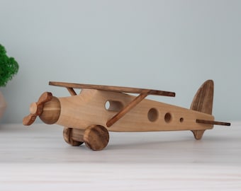 May include: A wooden toy airplane with a propeller, wheels, and a brown and natural wood finish.