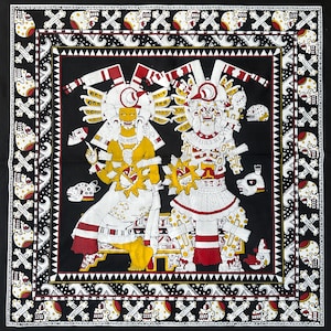 Puede incluir: Textil blanco y negro con un patrón repetido de calaveras y huesos cruzados. El centro presenta dos figuras en blanco, rojo y amarillo, con elaborados tocados y alas de plumas. Las figuras sostienen objetos circulares.