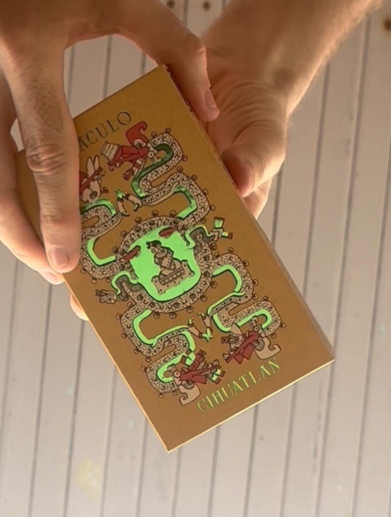 May include: A rectangular tan box featuring a central green illustration of a seated figure surrounded by a winding serpent design. The text ACULO is printed in the upper left corner and CIHUATLAN is printed in the lower right corner in green.