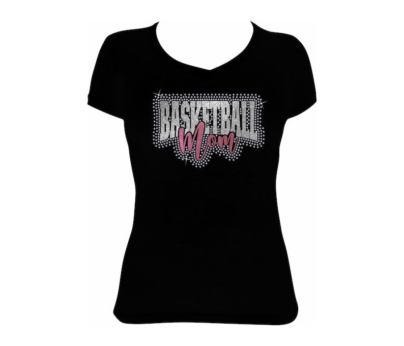 May include: Black V-neck t-shirt with the text "BASKETBALL Mom" in a rhinestone design. The word "BASKETBALL" is in silver rhinestones, and "Mom" is in pink rhinestones. The shirt is a solid black color.