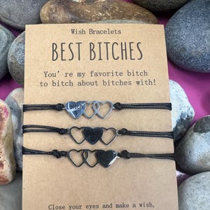 Puede incluir: Tres pulseras de deseos con dijes en forma de corazón. La tarjeta dice "BEST BITCHES" e incluye el texto "You're my favorite bitch to bitch about bitches with!" e instrucciones.
