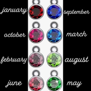 May include: Twelve round charms with different coloured gemstones, each charm has a silver loop at the top. The charms are labelled with the months of the year: January, February, March, April, May, June, July, August, September, October, November, and December.