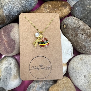 May include: A gold chain necklace with a charm of a hamburger, french fries, and a clear rhinestone. The necklace is displayed on a brown card with the text "Holly and Lili" in a circle.