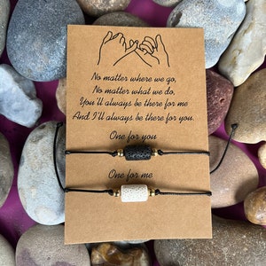 Puede incluir: Dos pulseras de amistad con cuentas de lava negra y blanca y cuentas doradas en cordones negros. La tarjeta dice "No importa a dónde vayamos, No importa lo que hagamos, Siempre estarás ahí para mí Y siempre estaré ahí para ti. Uno para ti Uno para mí"