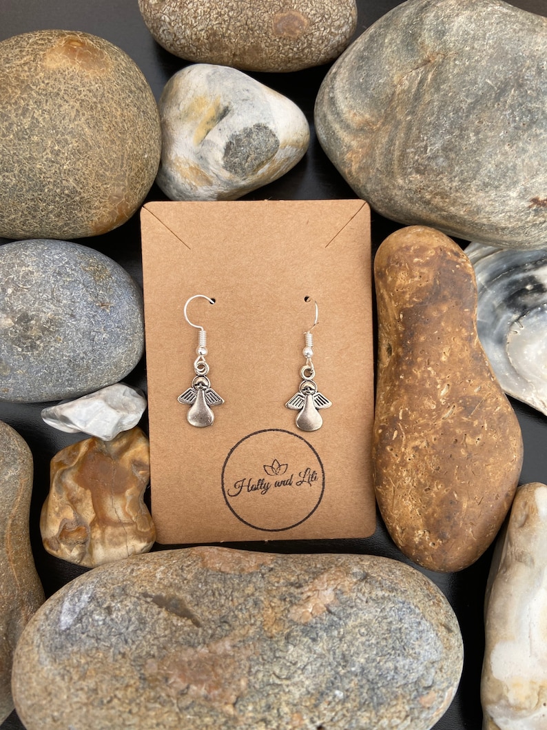 May include: Silver angel wing earrings displayed on a brown card with the text "Holly and Lita" in a circle.