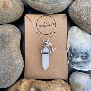 Puede incluir: Un collar de cadena plateada con un colgante de cristal blanco y un dije plateado con la letra "Z" colgando de él. El collar se muestra en una tarjeta marrón con el texto "Holly and Liti" impreso en ella.