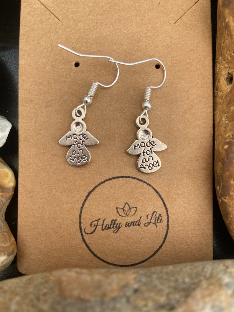 May include: Silver angel earrings with the inscription "Made for an Angel" on a brown card with the text "Holly and Lili" in a circle.