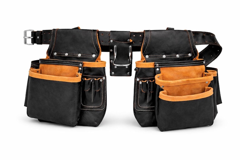 May include: A black and tan leather tool belt with multiple pockets and pouches. The belt has a silver buckle and rivets. The interior of the pockets is tan, and the exterior is black. The tool belt is designed for construction or carpentry.