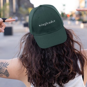 Może przedstawiać: Ciemnozielona czapka z daszkiem z haftowanym na przodzie białym napisem "wingleader".