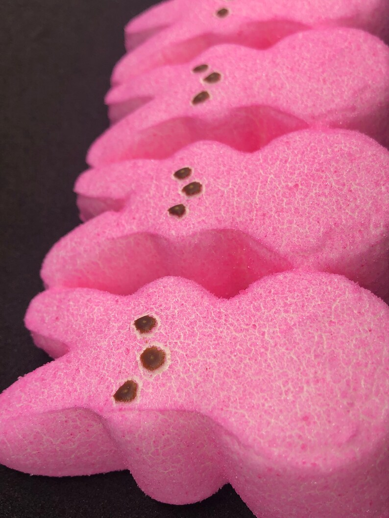 May include: A stack of pink marshmallow Peeps, a popular Easter treat, with chocolate chips for eyes.