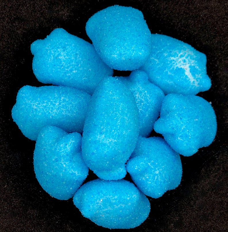 May include: A group of nine blue, sugar-coated candies shaped like small, rounded pears.