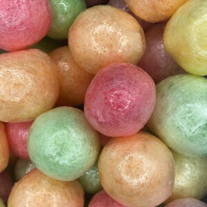 May include: A close-up of a pile of colorful, round, textured, bubble wrap packing peanuts. The peanuts are in shades of pink, orange, green, and yellow.