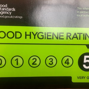 May include: A green and black food hygiene rating sticker with a white number 5 in a black circle. The text "VERY GOOD" is below the number. The sticker is from the Food Standards Agency and includes the website food.gov.uk/ratings.