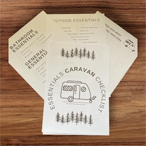 May include: A set of white paper checklists for caravan essentials, bathroom essentials, and general essentials. The central checklist features a caravan illustration and the text "Essentials Caravan Checklist". Other checklists include items like towels, toilet fluids, and tools.