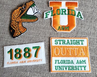 May include: Four embroidered patches featuring the Florida A&M University logo. The patches are white with green and orange lettering and designs. One patch features a snake, another a letter U, another the year 1887, and the last patch says "Straight Outta Florida A&M University".