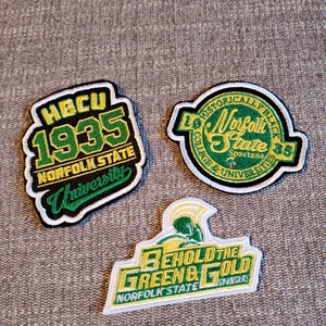 May include: Three embroidered patches featuring the Norfolk State University logo. The first patch is green and black with the text "HBCU 1935 NORFOLK STATE University". The second patch is green and black with the text "Historically Black College & University Norfolk State Spartans 1935". The third patch is green and gold with the text "Behold the Green & Gold Norfolk State Spartans".