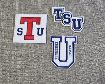 Peut inclure: Quatre écussons brodés avec les lettres "TSU" et "Tennessee State University". Les écussons sont blancs avec des accents bleus et rouges. Un écusson est carré, les autres sont façonnés pour s'adapter aux lettres.