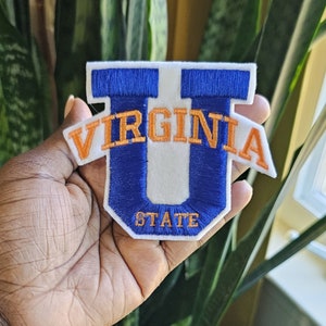 May include: A white felt patch with a blue embroidered "U" and the text "VIRGINIA STATE" in orange embroidery.