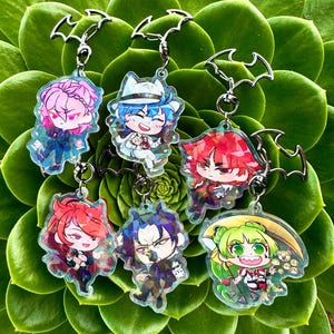 May include: Six colorful character charms with holographic glitter accents. Each charm features a different character with a unique design and is attached to a silver bat-shaped keychain.