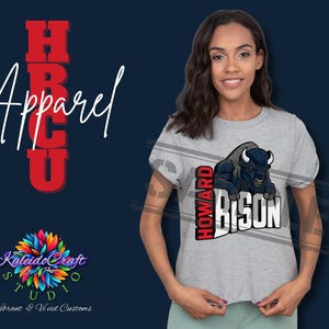 Puede incluir: Camiseta gris claro con un gráfico de un bisonte azul y el texto "HOWARD BISON" en blanco y rojo. La palabra "Apparel" está escrita verticalmente en rojo. La camiseta la lleva una persona.