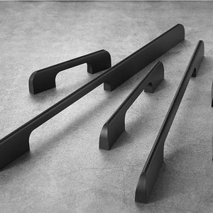 May include: Five black metal cabinet pulls of varying lengths. The pulls have a simple, modern design with rounded edges.