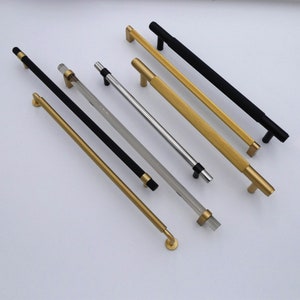 Peut inclure: Assortiment de poignées de meubles de différentes finitions, notamment noir, or et argent. Les poignées sont en métal et ont des styles et des longueurs différents.