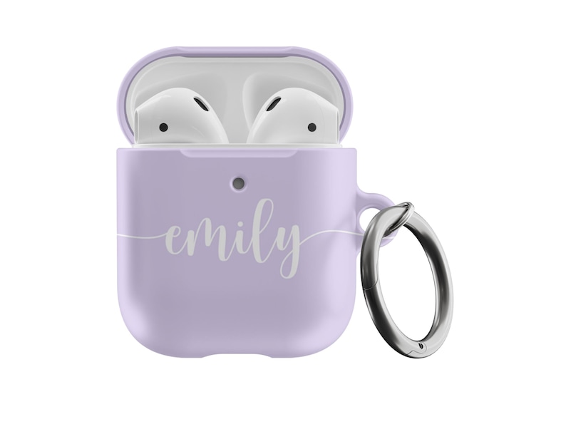 May include: A lilac-colored AirPods case with the name "emily" in a cursive font. The case is open, revealing white earbuds. A silver carabiner clip is attached to the side for easy carrying.